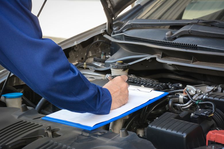 Gutachter in der Werkstatt der den Motor eines Autos überprüft